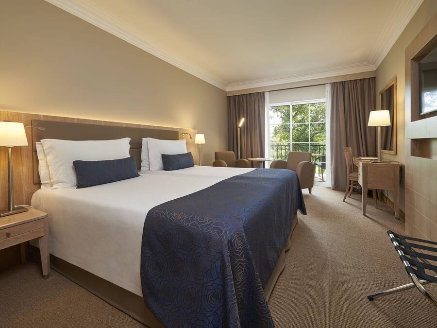 Une chambre d’hôtel avec un grand lit, des tables de chevet, un bureau et une chaise.