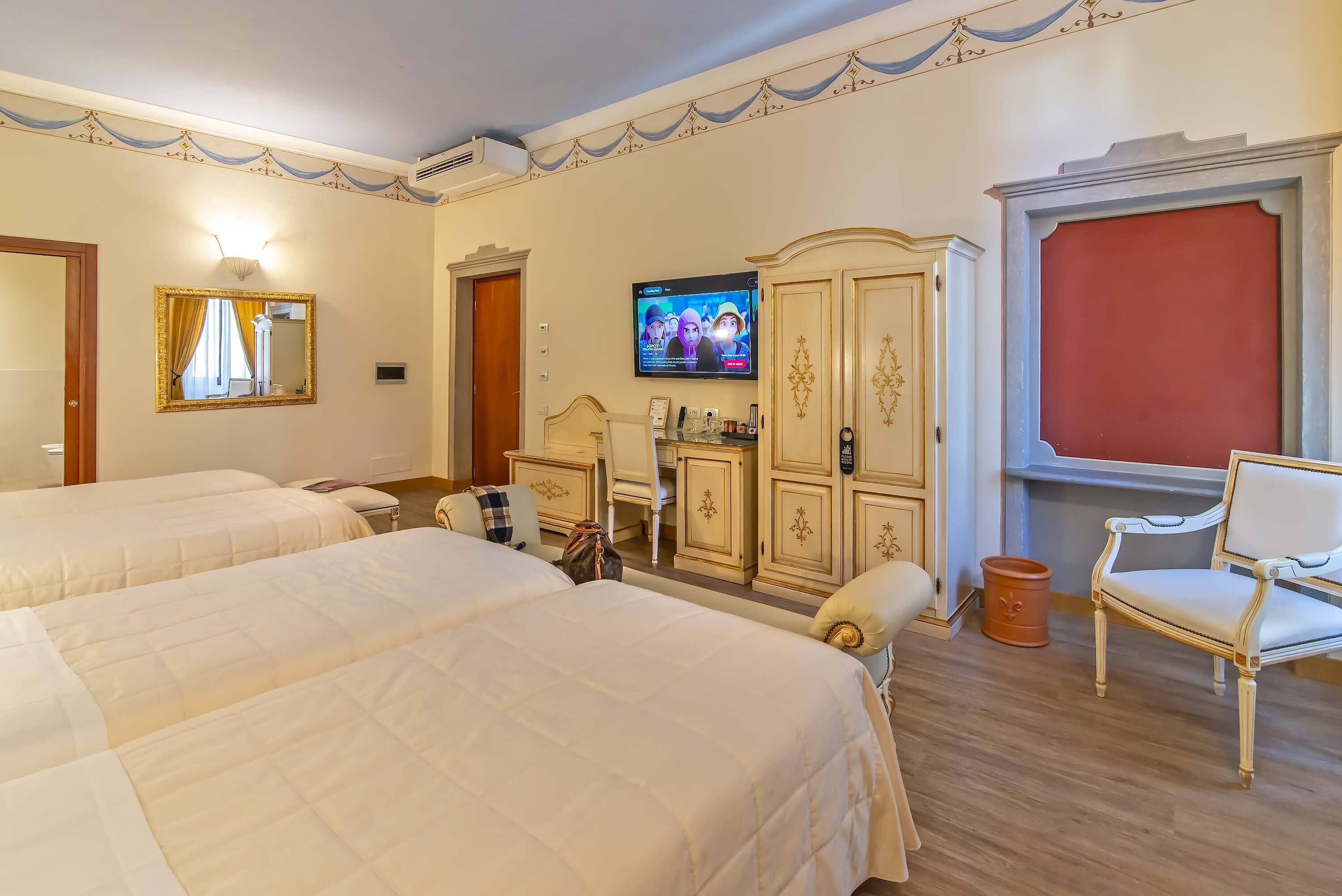 Habitación de hotel con dos camas, televisión, armario y una silla.
