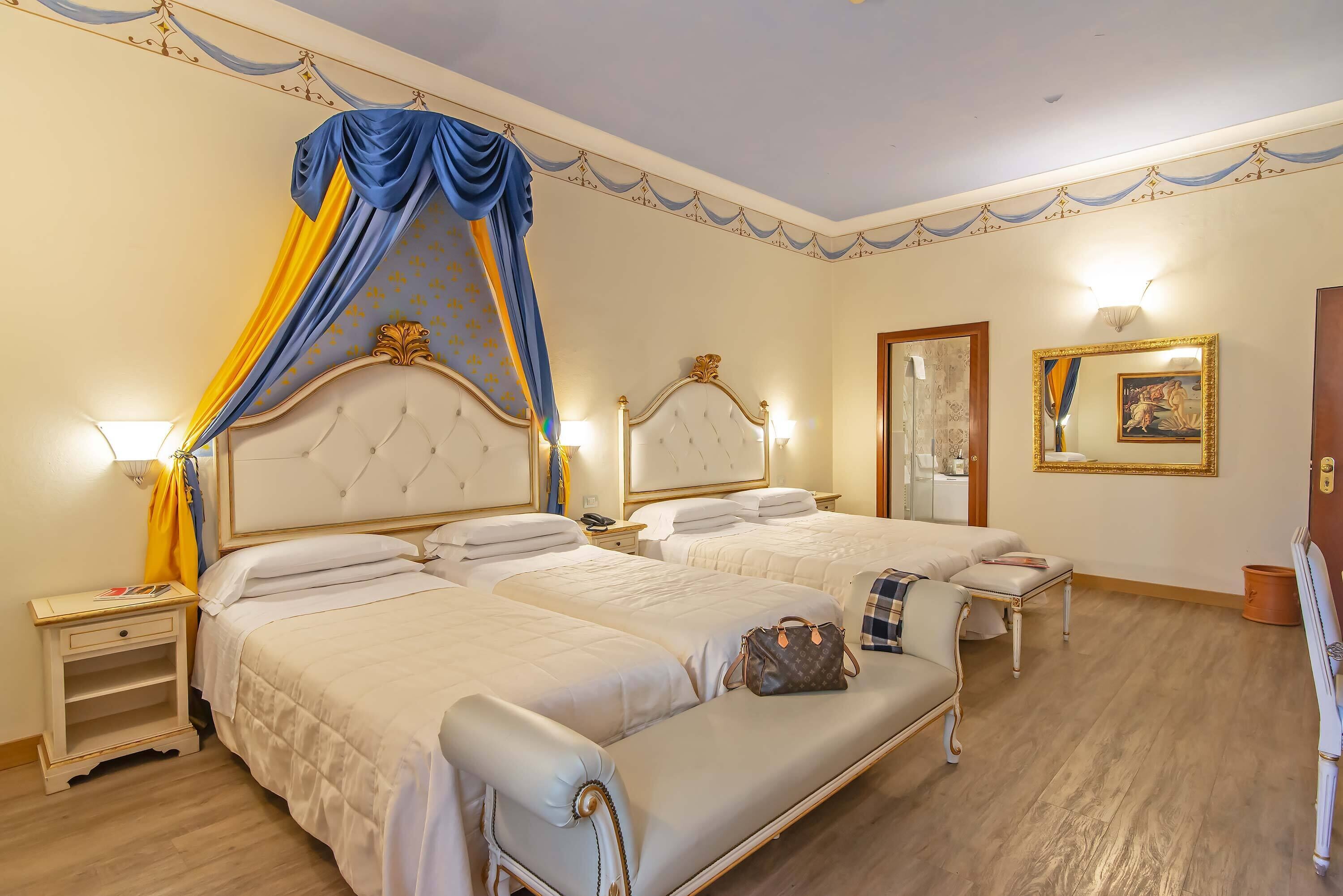Une chambre d’hôtel avec deux lits, une table de chevet, une chaise et un miroir.