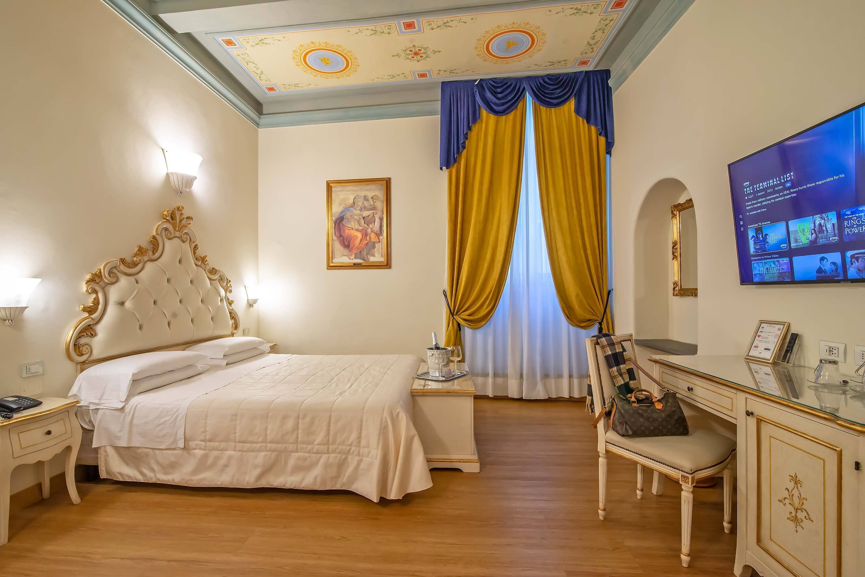 A hotel room with a large bed, a desk with a chair, a television, and a painting on the wall.