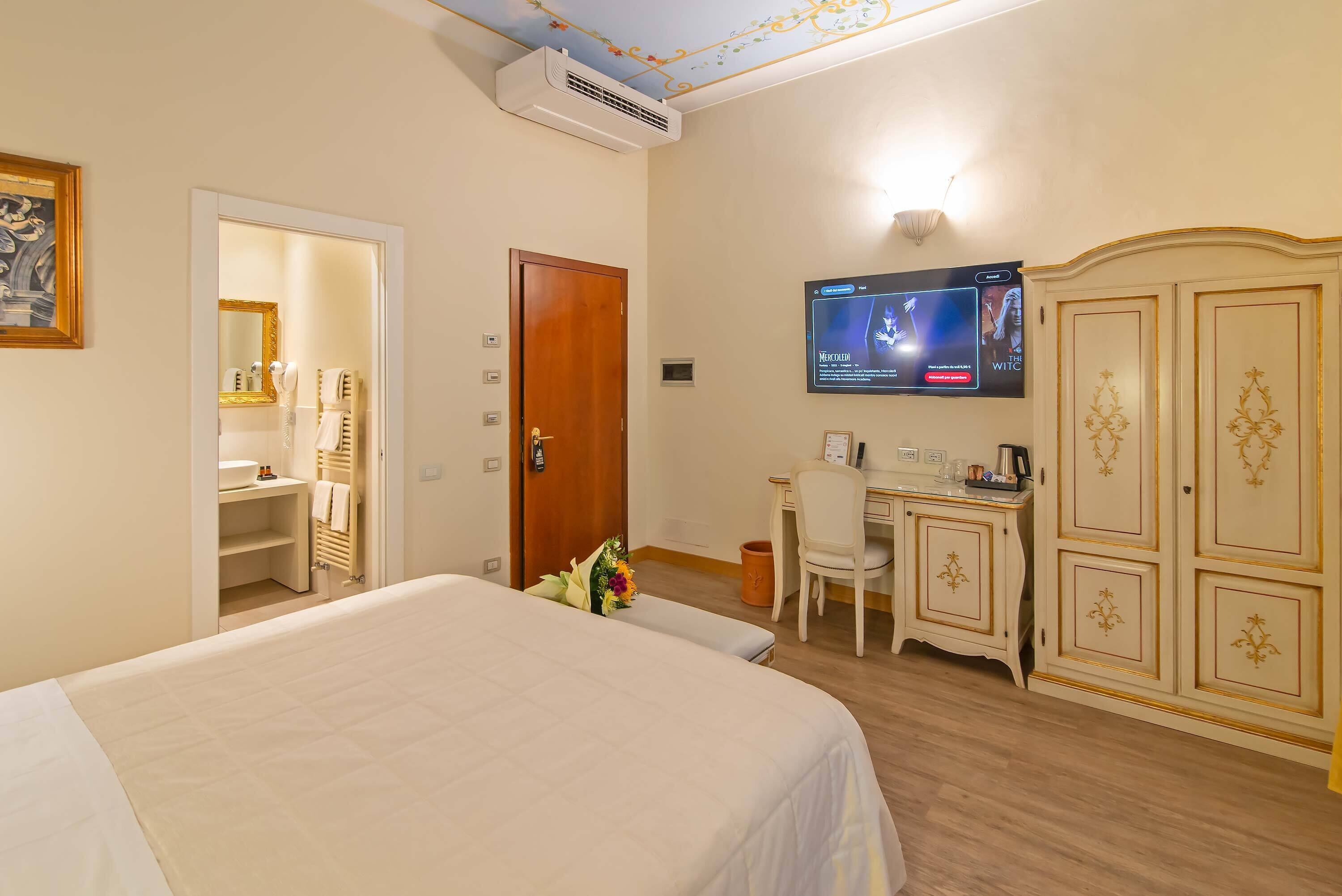 A hotel room with a bed, a desk, a TV, and a wardrobe.