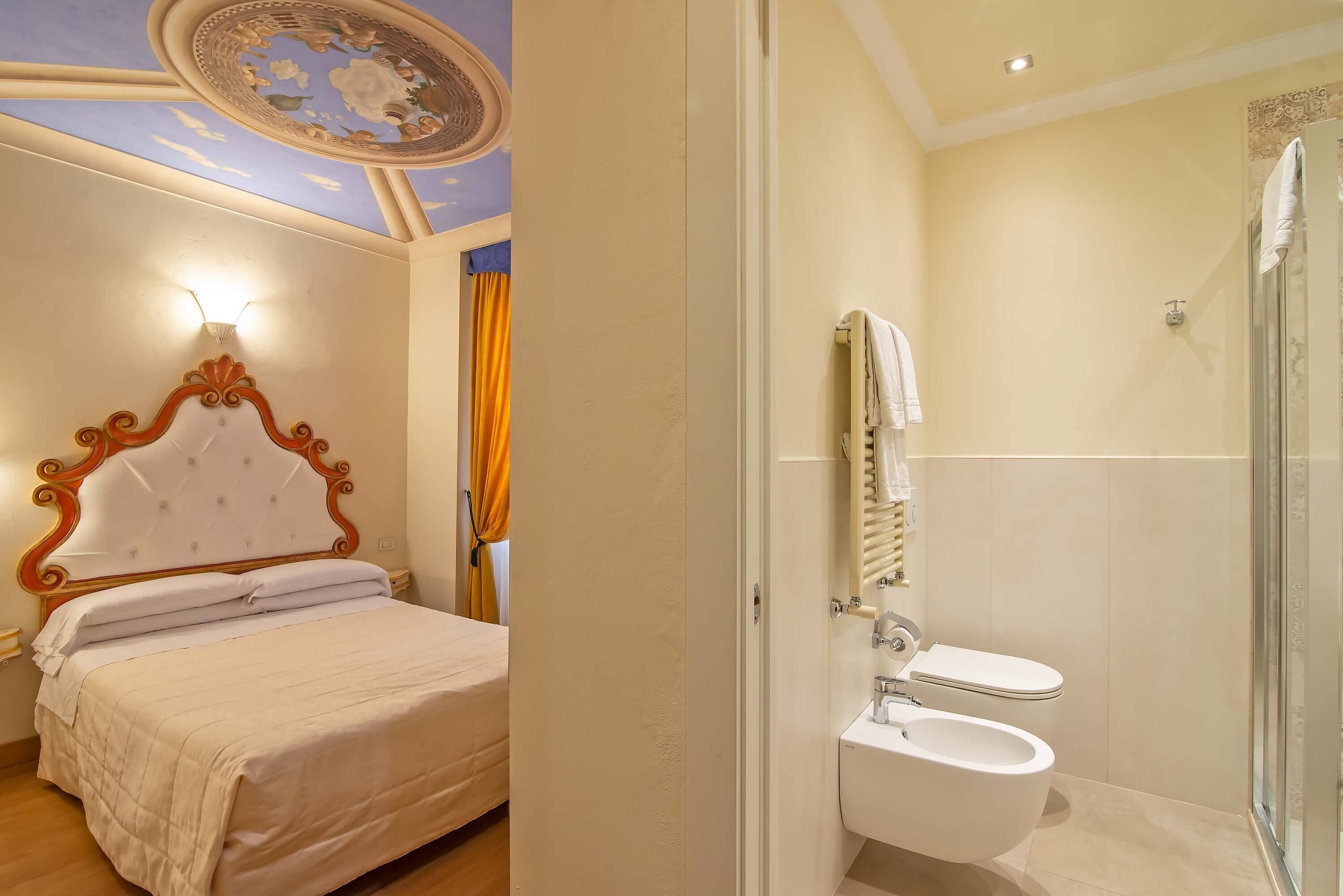A bedroom with a large bed, a ceiling fan, and a bathroom with a toilet and shower.