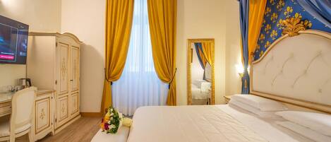 A hotel room with a large bed, a desk with a chair, a wardrobe, and a television.