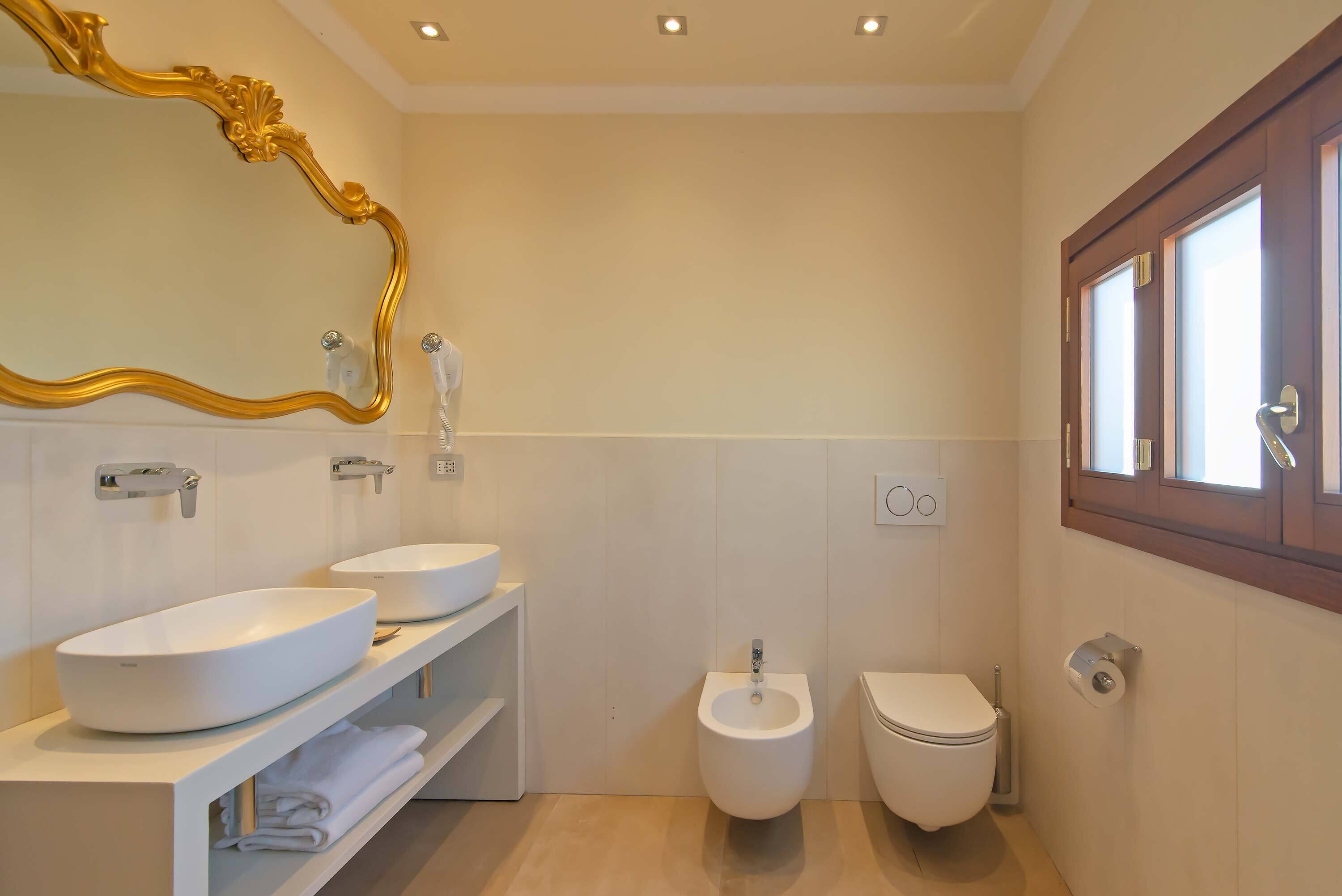 A modern bathroom with two sinks, a bidet, and a toilet.