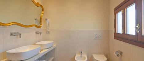 A modern bathroom with two sinks, a bidet, and a toilet.