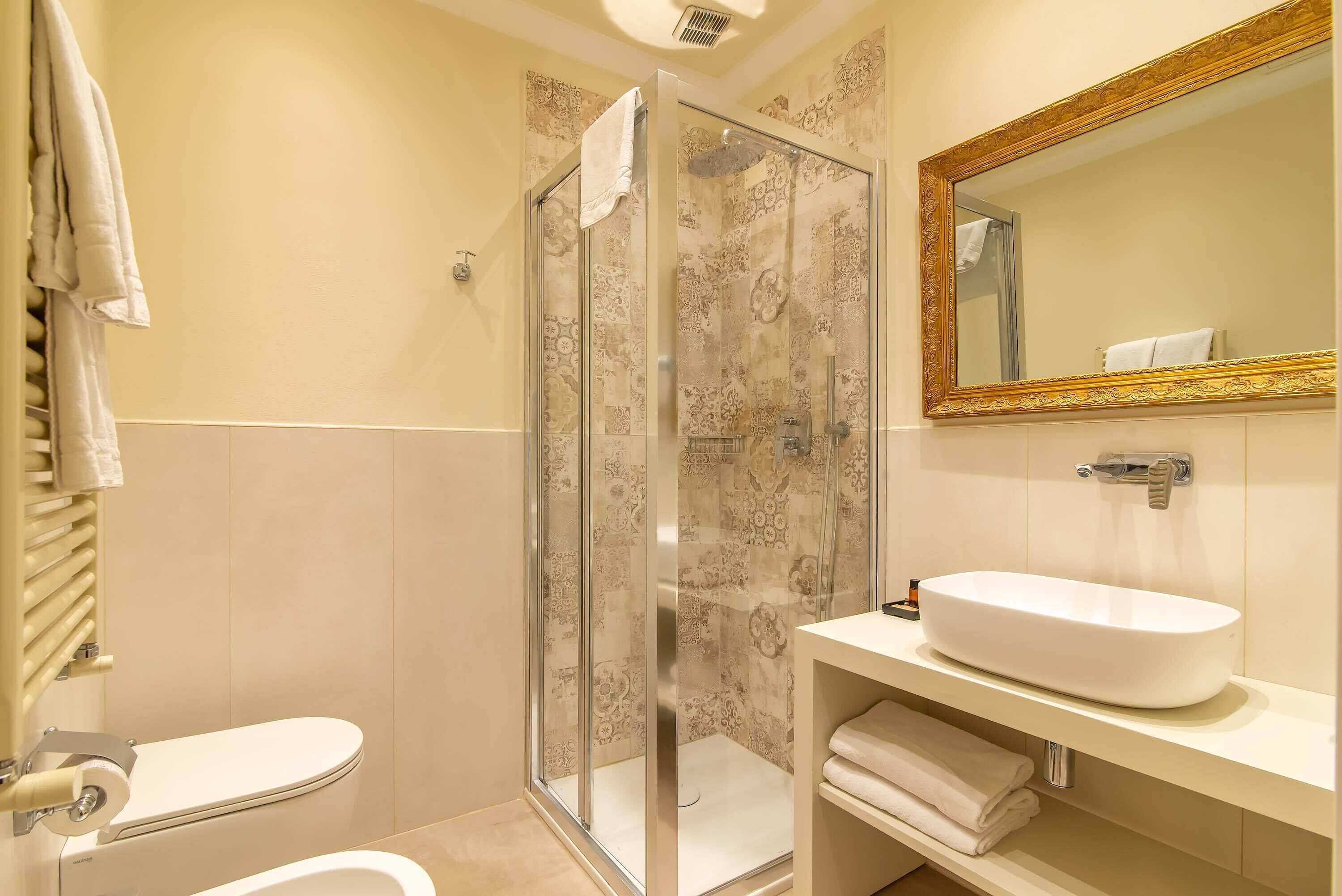 A bathroom with a glass-enclosed shower, a white sink, and a toilet.