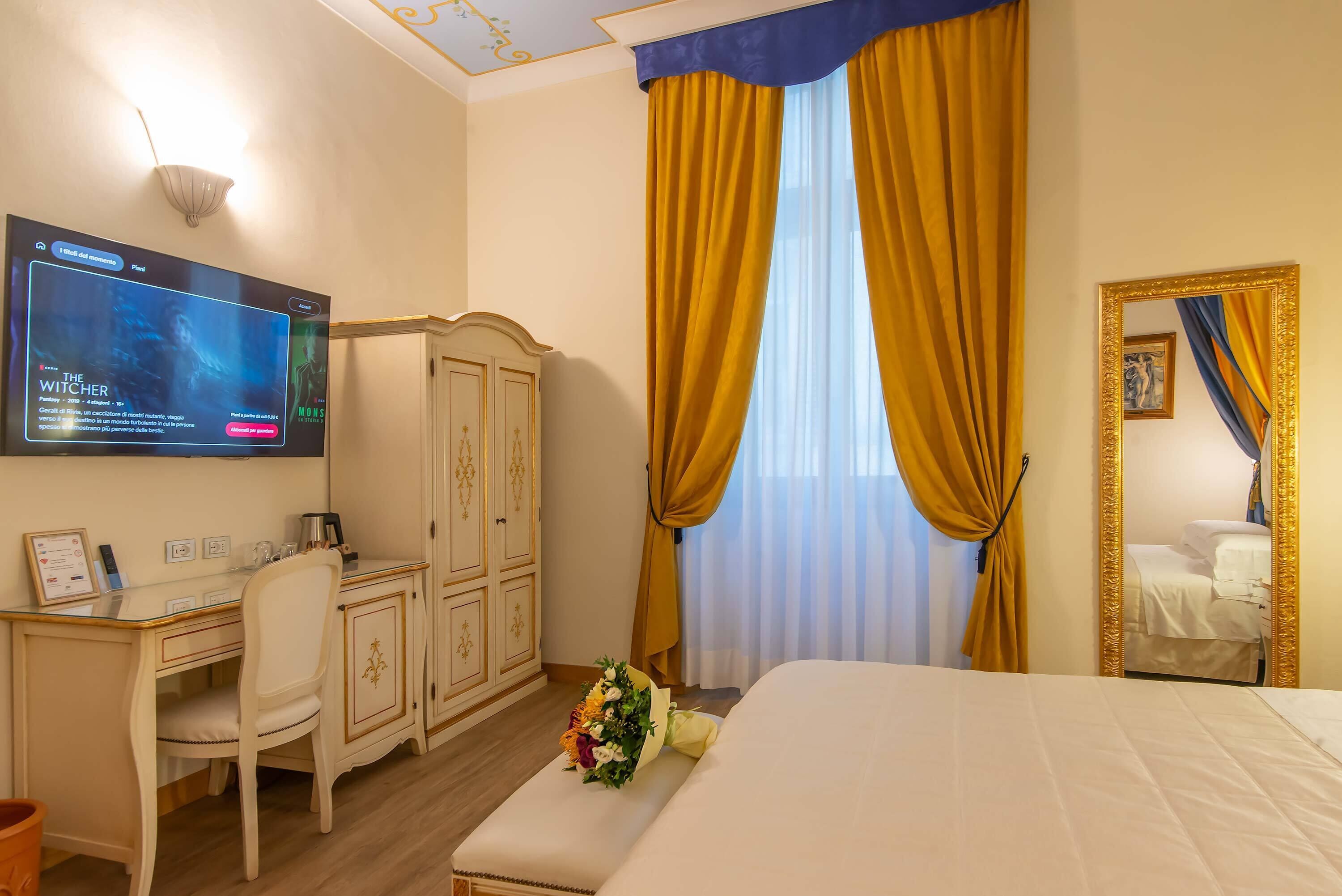 Ein Hotelzimmer mit Bett, Schreibtisch mit Computer, Kleiderschrank und großem Spiegel.