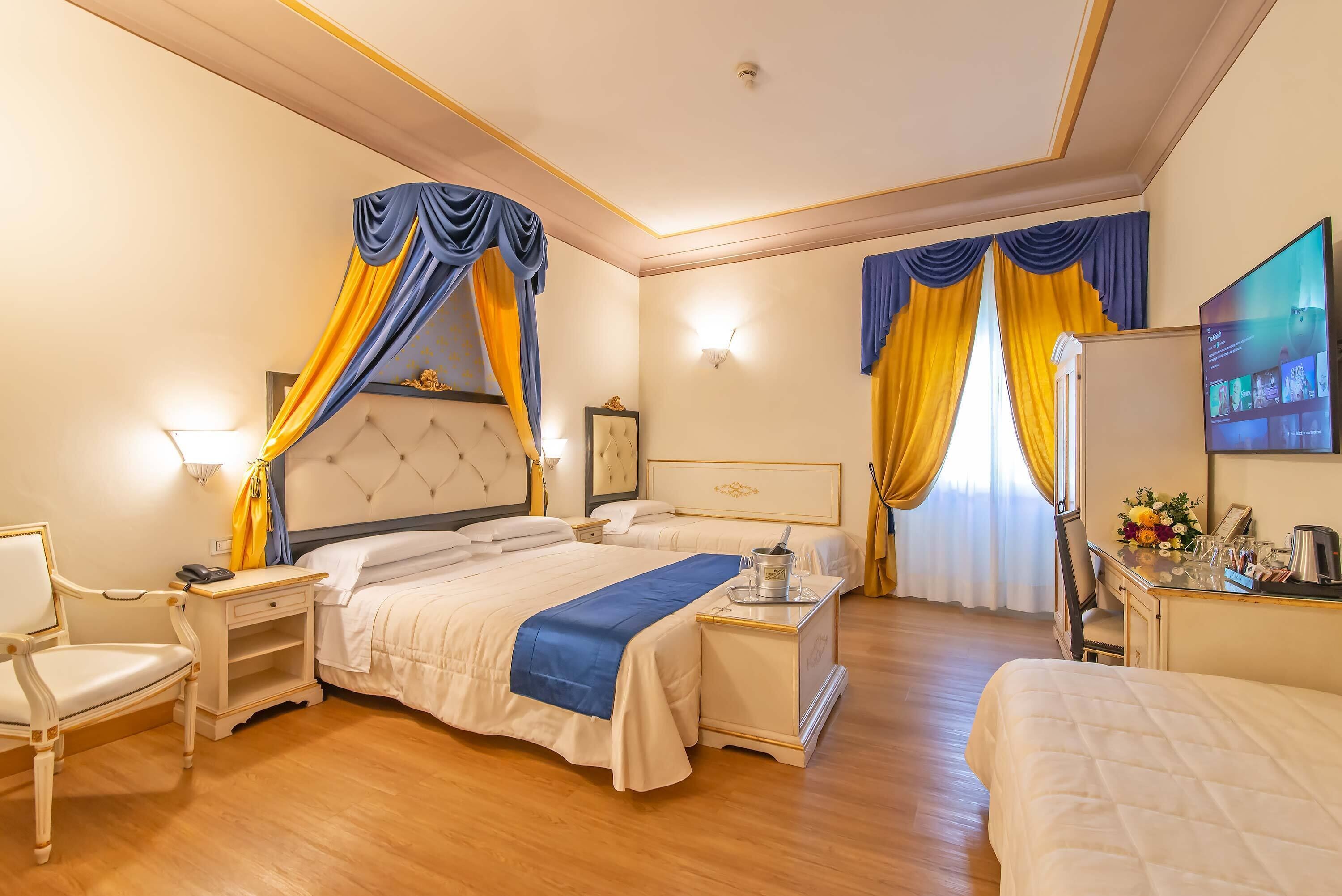 A hotel room with a large bed, a desk, a chair, and a television.