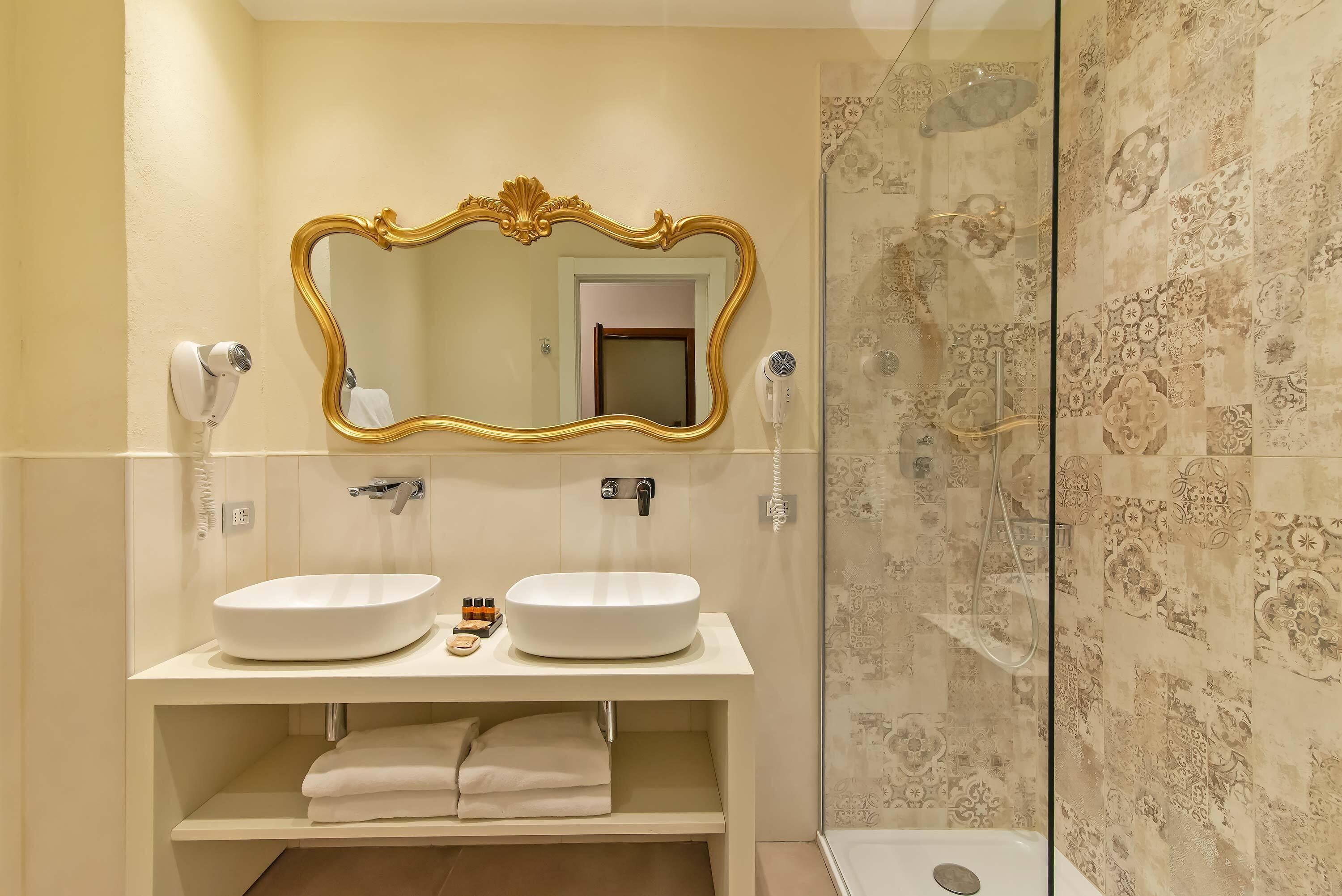 A bathroom with two sinks, a large mirror, and a shower area.