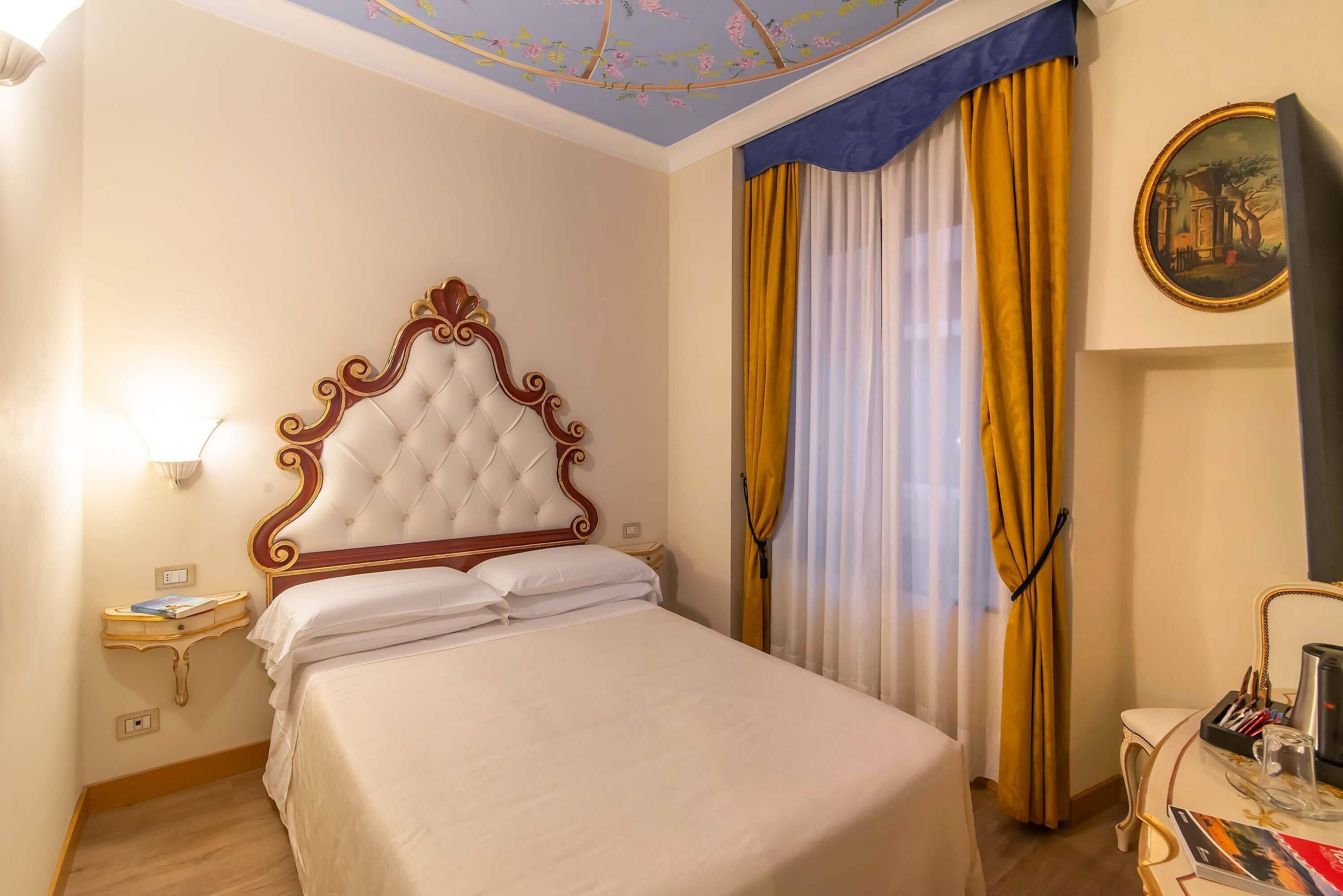 Un lit bien fait, avec une tête de lit capitonnée, une table de chevet avec une lampe et un tableau accroché au mur.