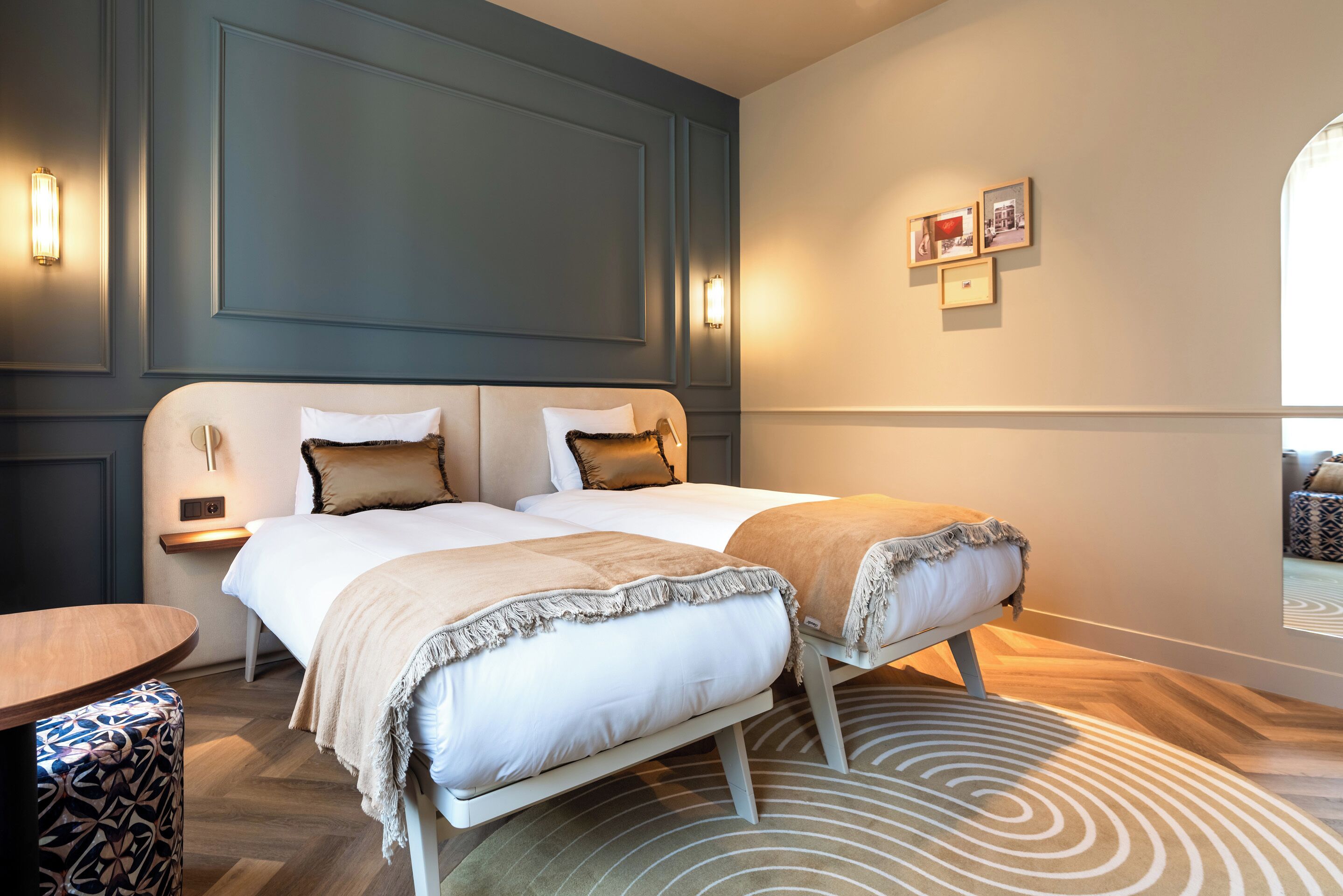 A modern hotel room with a large bed, bedside tables, and a view of the city through a window.