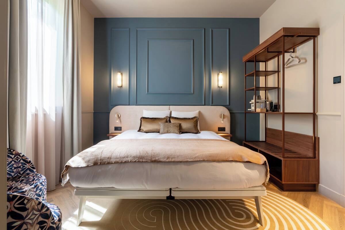 A bedroom with a bed, bedside tables, a built-in wooden shelf, and a patterned rug.