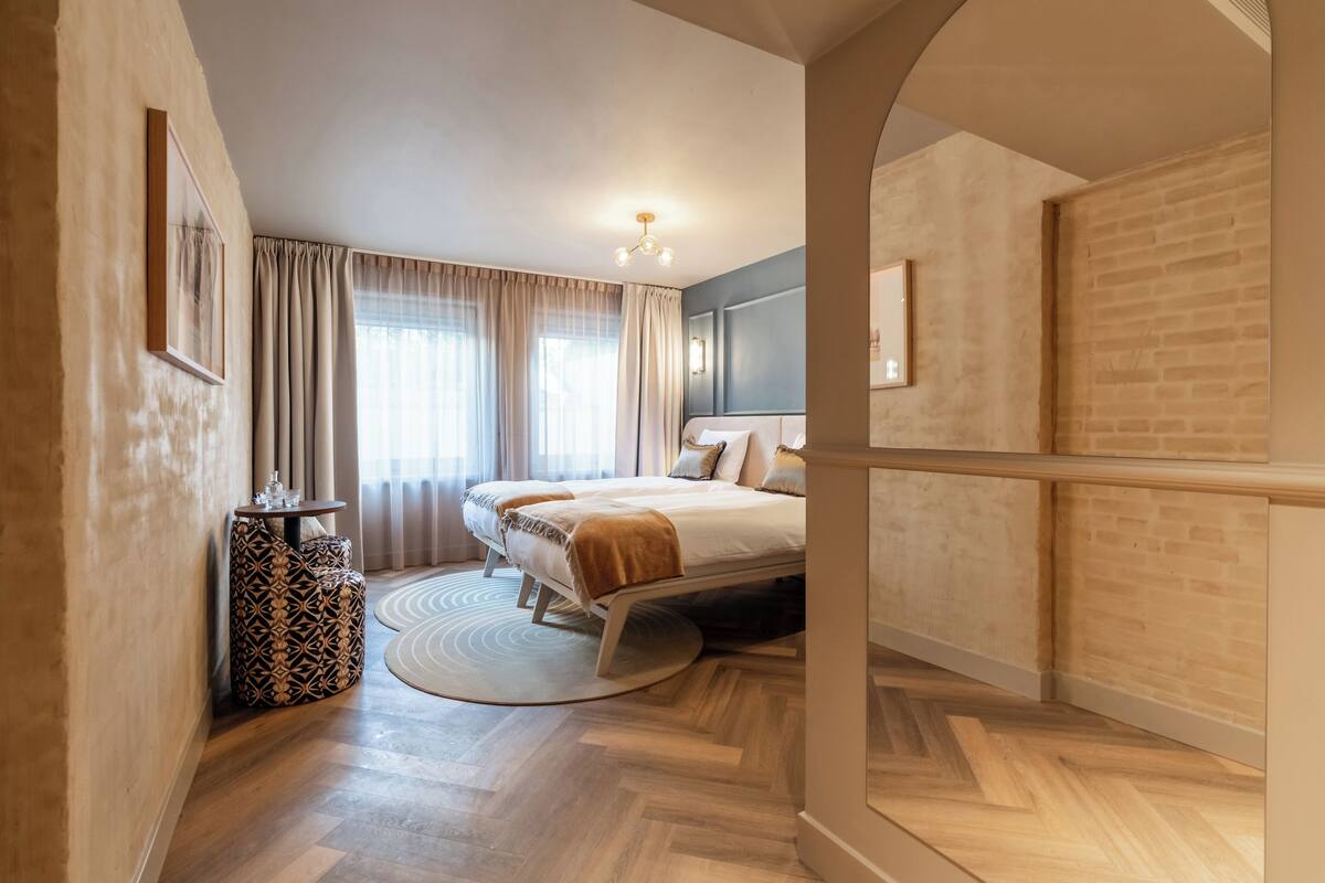 A modern hotel room with a bed, a side table, and a round rug.
