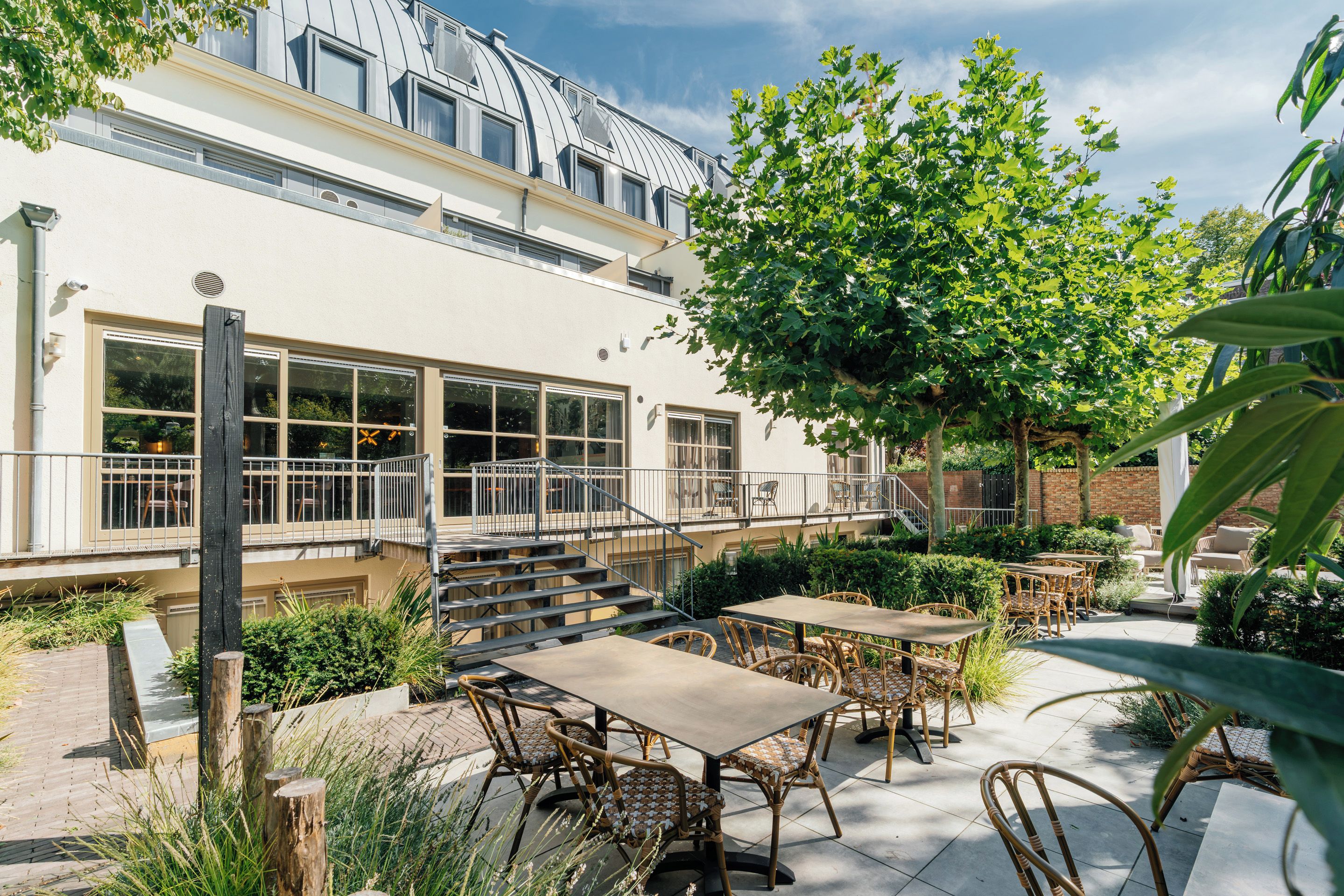 A building with a flat roof, large windows, and outdoor seating with wicker furniture.