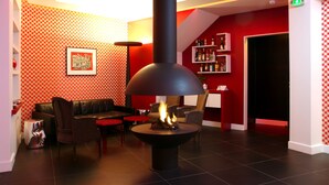 A modern interior with a fireplace, red patterned walls, and a black ceiling. - Hotel Opéra Opal (Paris)