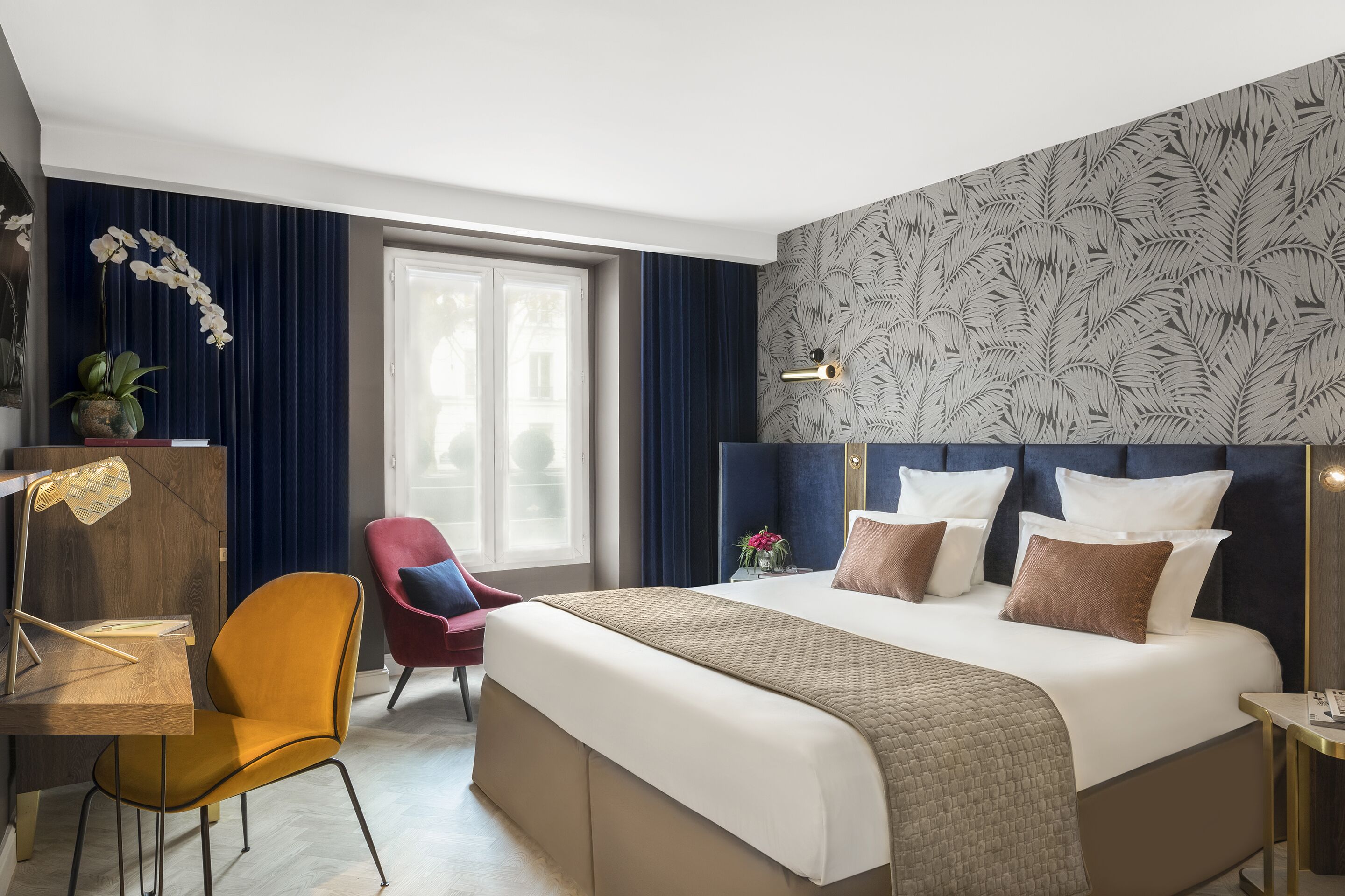 Habitación de hotel con una cama grande, un escritorio, una silla y una ventana con cortinas.