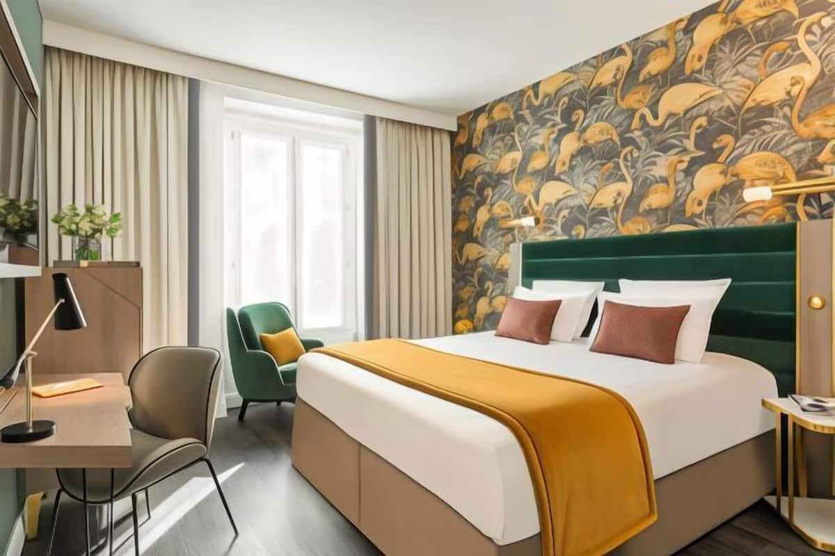 A hotel room with a bed, a desk, a chair, and a large window.