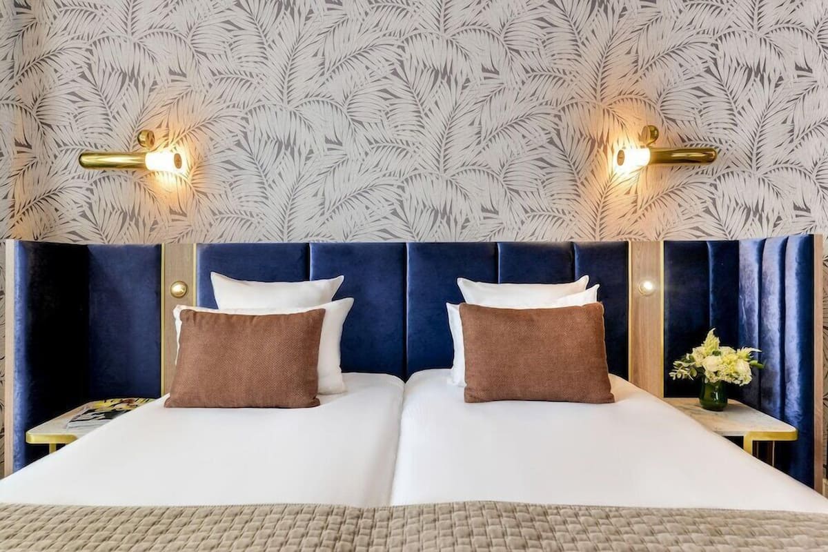 A double bed with a blue headboard, two brown pillows, and a white bedspread.