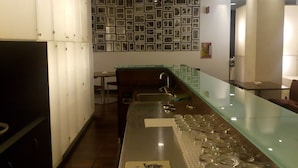 A modern kitchen with a glass counter, stainless steel appliances, and a wall of framed photos. - Hotel Igea (Brescia)