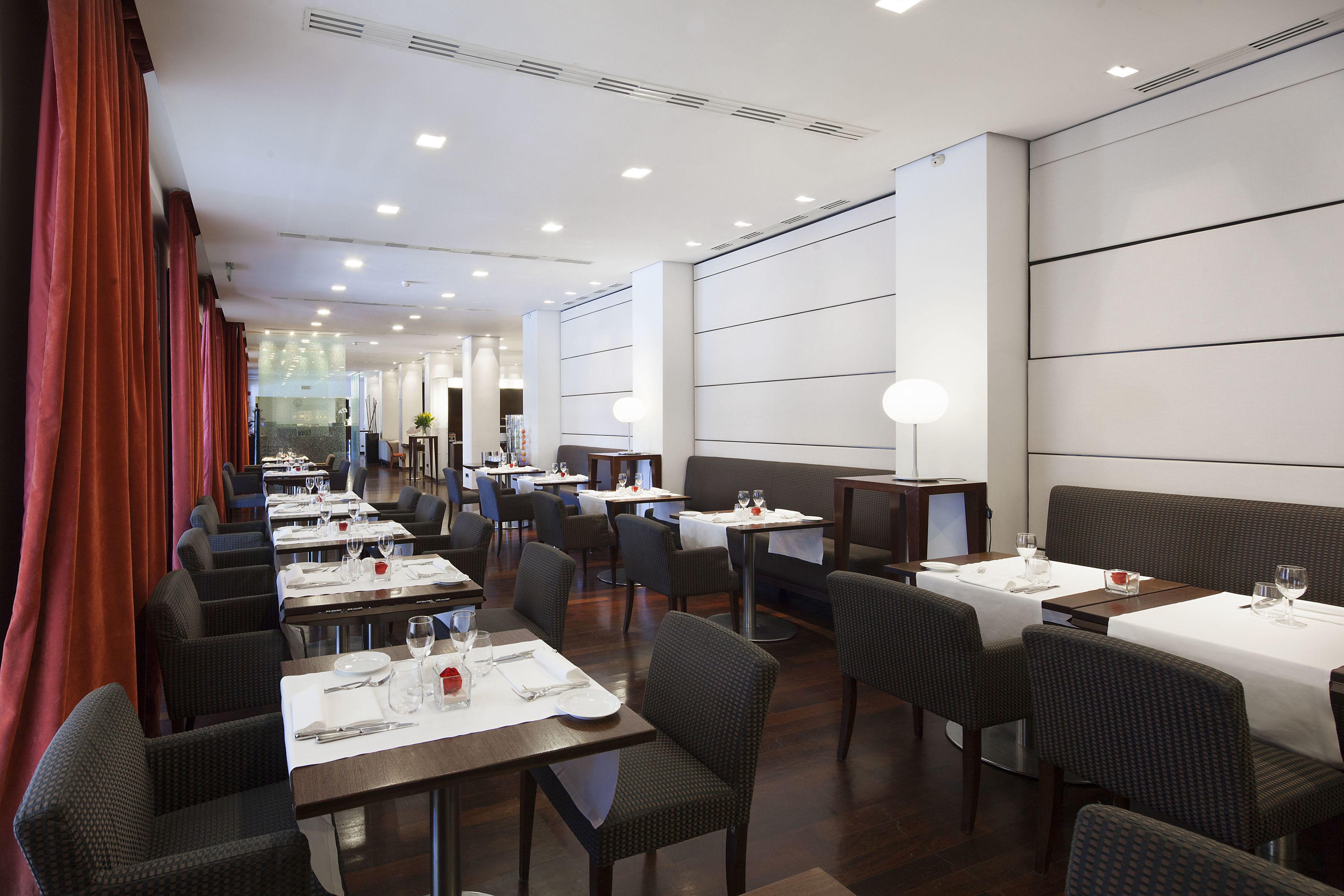 A restaurant with multiple tables and booths, each set with white tablecloths and silverware.