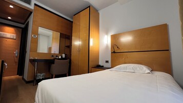 Une chambre d’hôtel comprenant un lit, un bureau, une chaise, une armoire et un miroir.