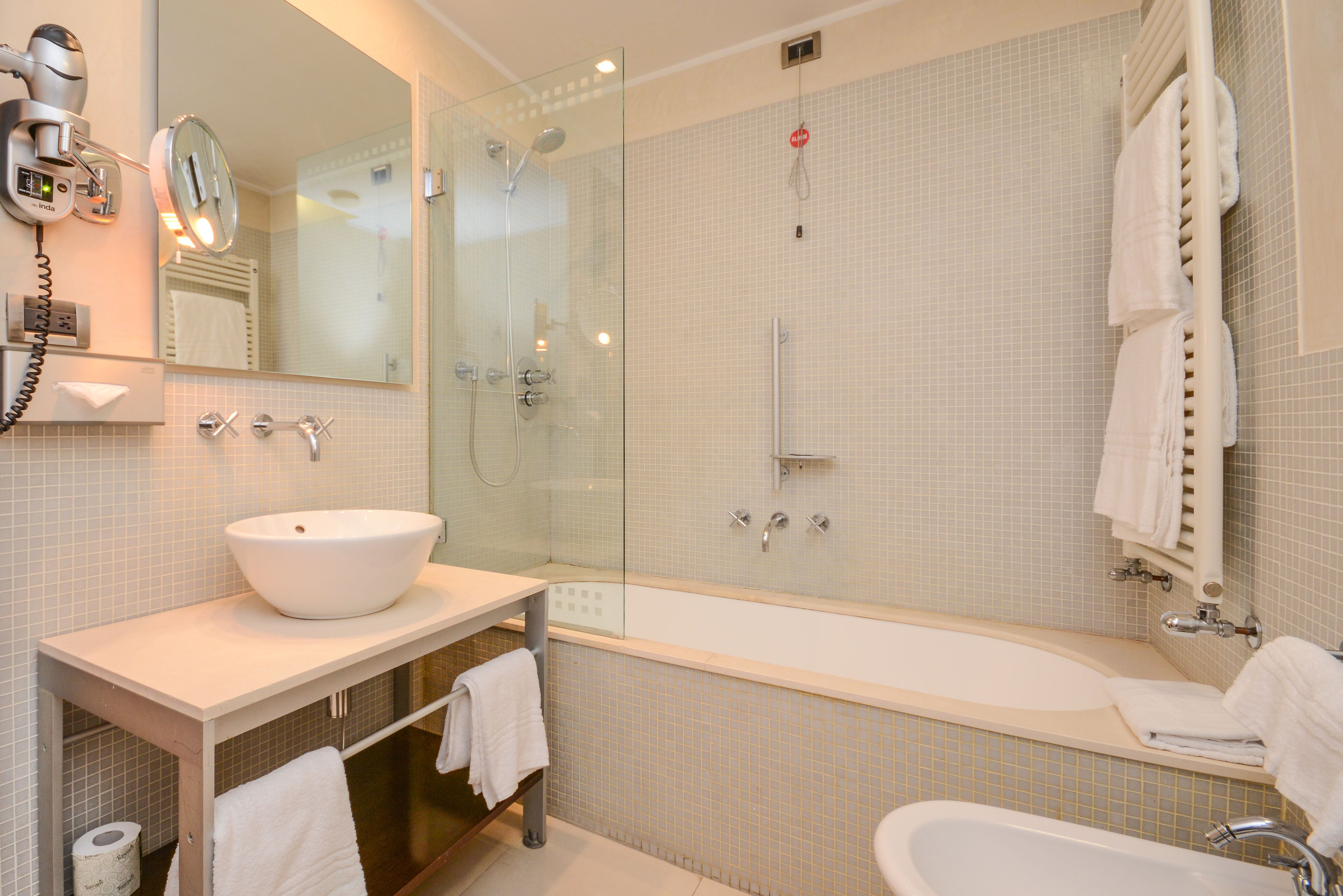 A modern bathroom with a large bathtub, a glass-enclosed shower, a sink, and a mirror.