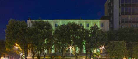 Un hotel moderno con fachada plana, múltiples ventanas y una entrada bien iluminada.