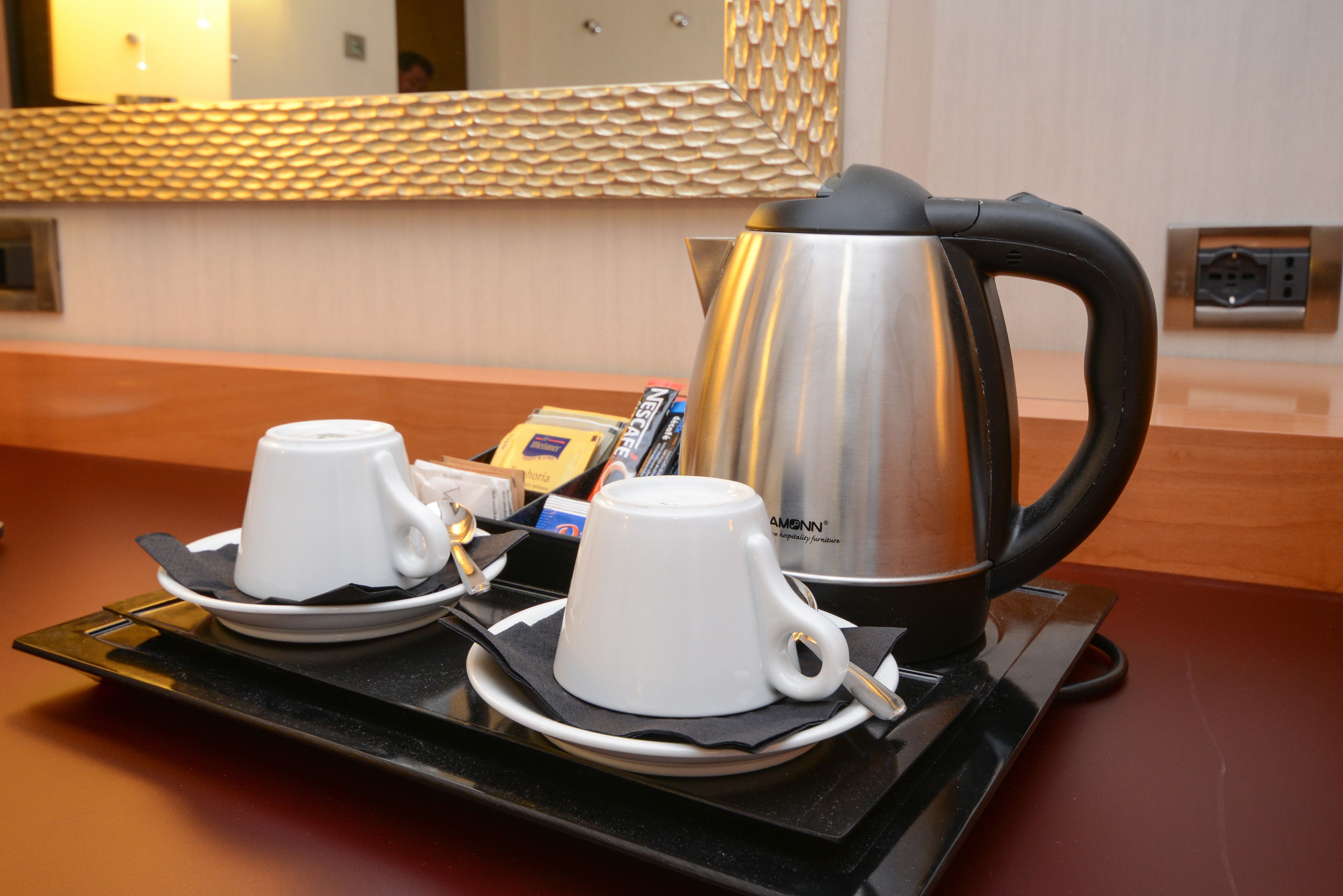 Una estación de café con una cafetera, dos tazas y una bandeja.