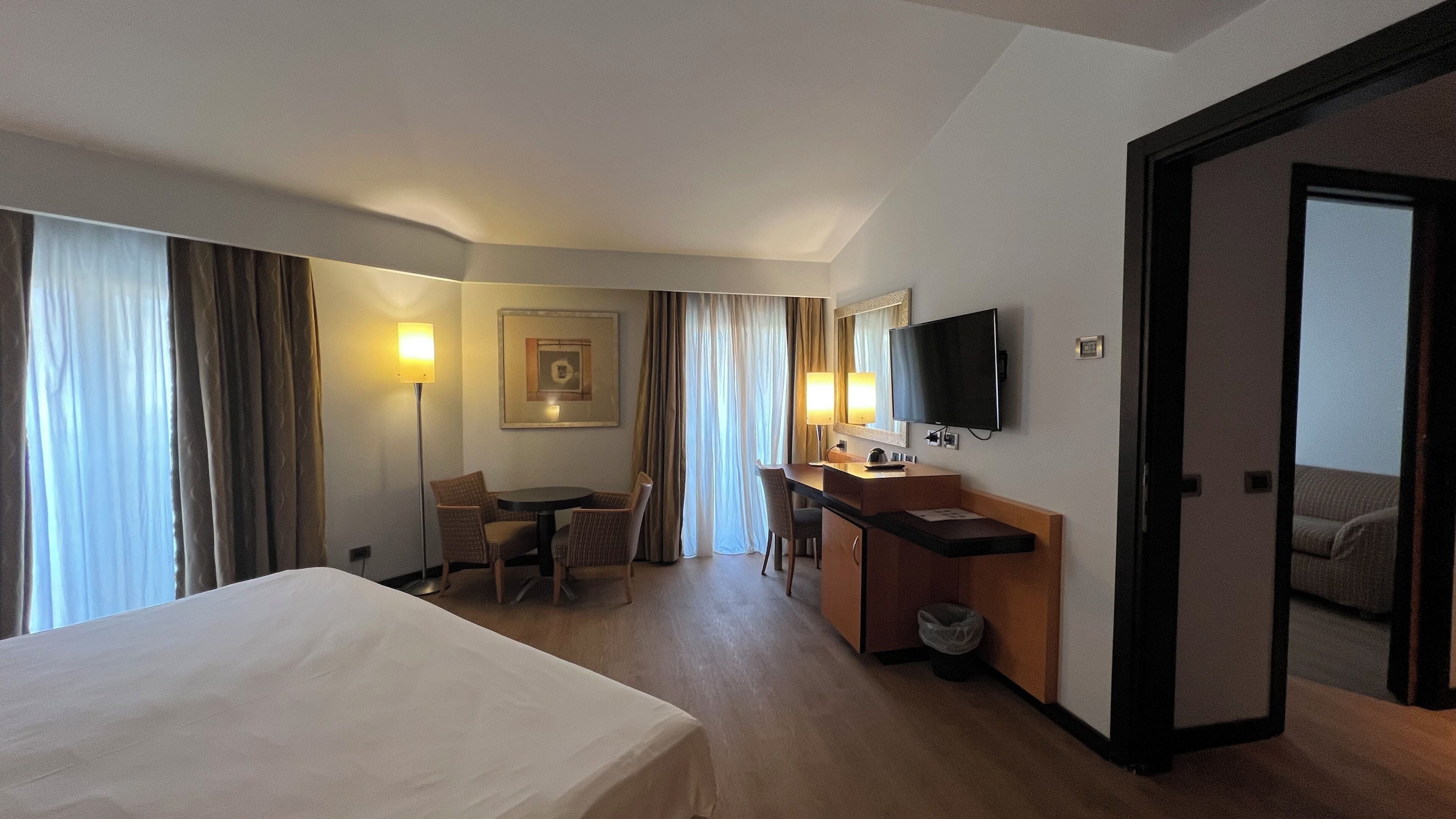Une chambre d’hôtel équipée d’un lit, d’un bureau, d’une chaise, d’une télévision et de rideaux.