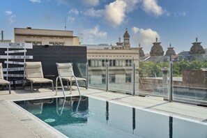 Piscina en la azotea con sillones de descanso y un cartel con frases motivacionales.