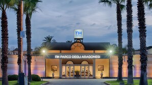 A hotel entrance with a sign reading "NH PARCO DEGLI ARAGONESI" and "NH HOTELS" above.