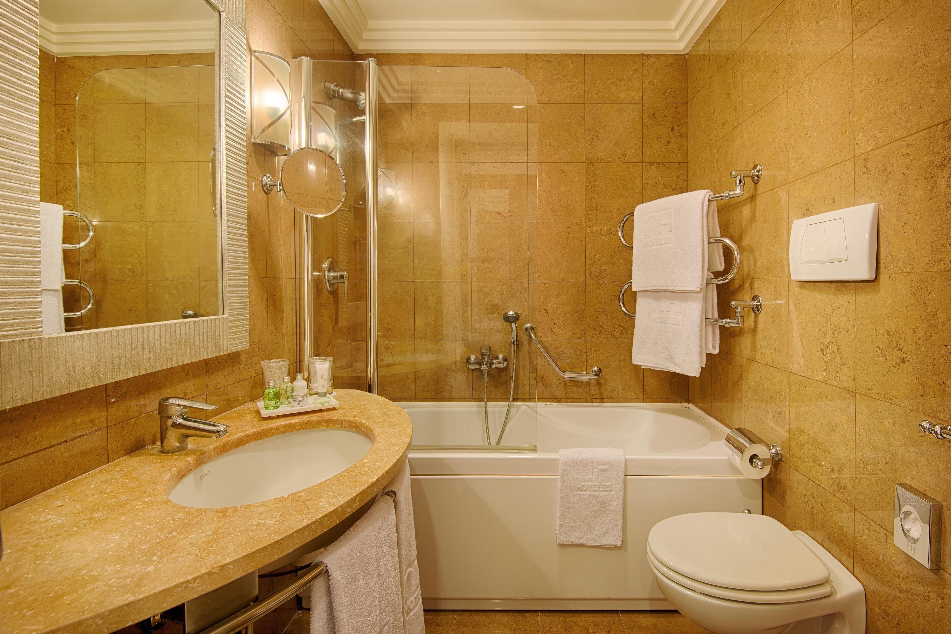 A bathroom with a sink, mirror, bathtub, and toilet.