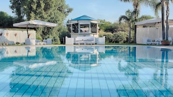 Una piscina al aire libre de temporada, sombrillas