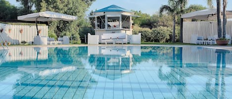 Una piscina al aire libre de temporada, sombrillas