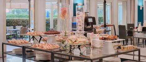 A buffet setup with various food items and a coffee station in a modern hotel setting.