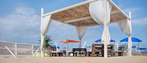 Un área de descanso en la playa con bancos de madera y sombrillas.