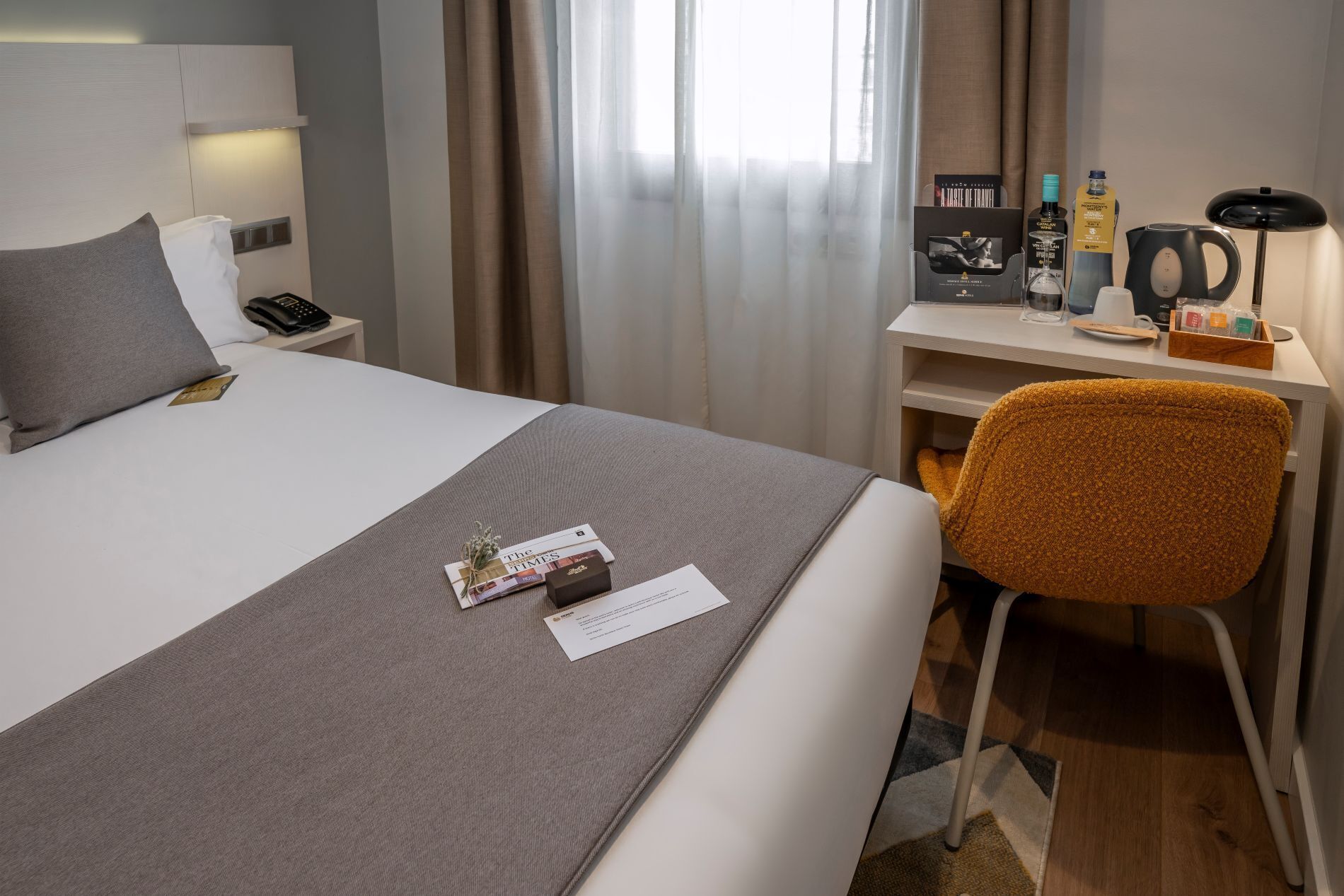 Ein Hotelzimmer mit Bett, Schreibtisch, Stuhl und verschiedenen Annehmlichkeiten wie Telefon, Kaffeemaschine und Toilettenartikeln.