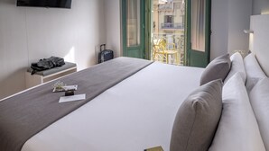 Una habitación de hotel con una cama, un escritorio con un bolso, una silla y una maleta.