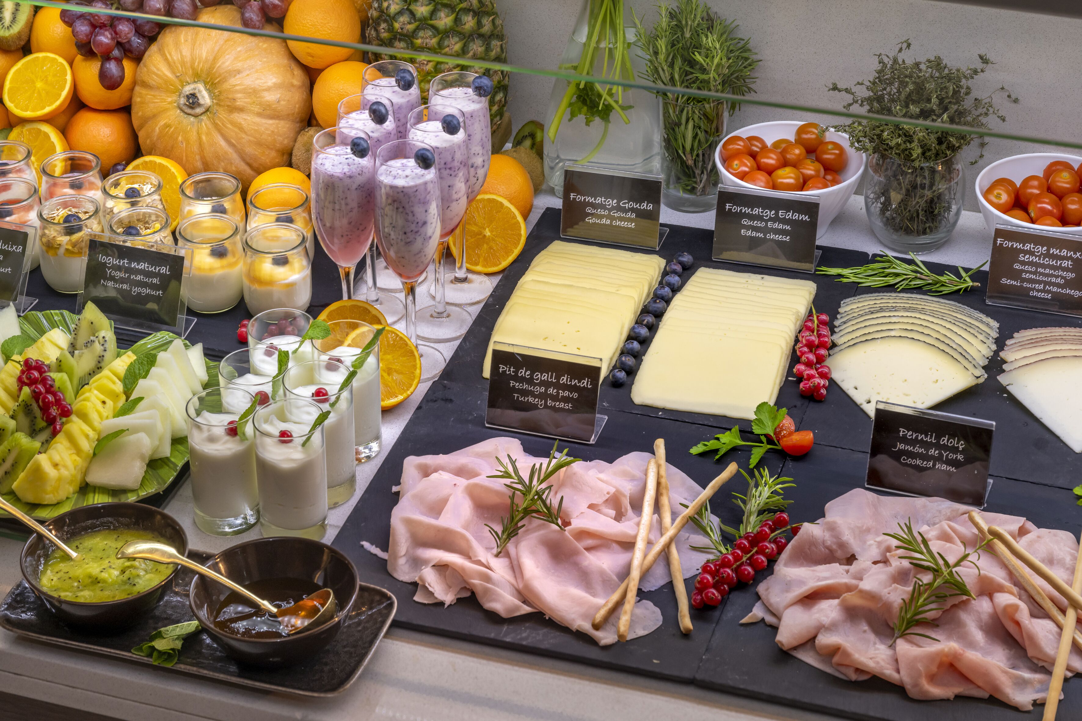 A charcuterie board with various cheeses, meats, fruits, and beverages.