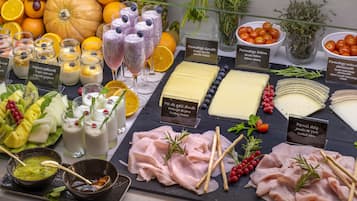 A charcuterie board with various cheeses, meats, fruits, and beverages.