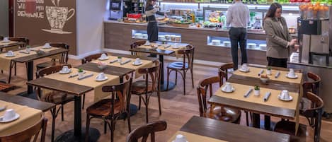 A restaurant with wooden tables and chairs, a buffet area, and a wall with a welcome message.