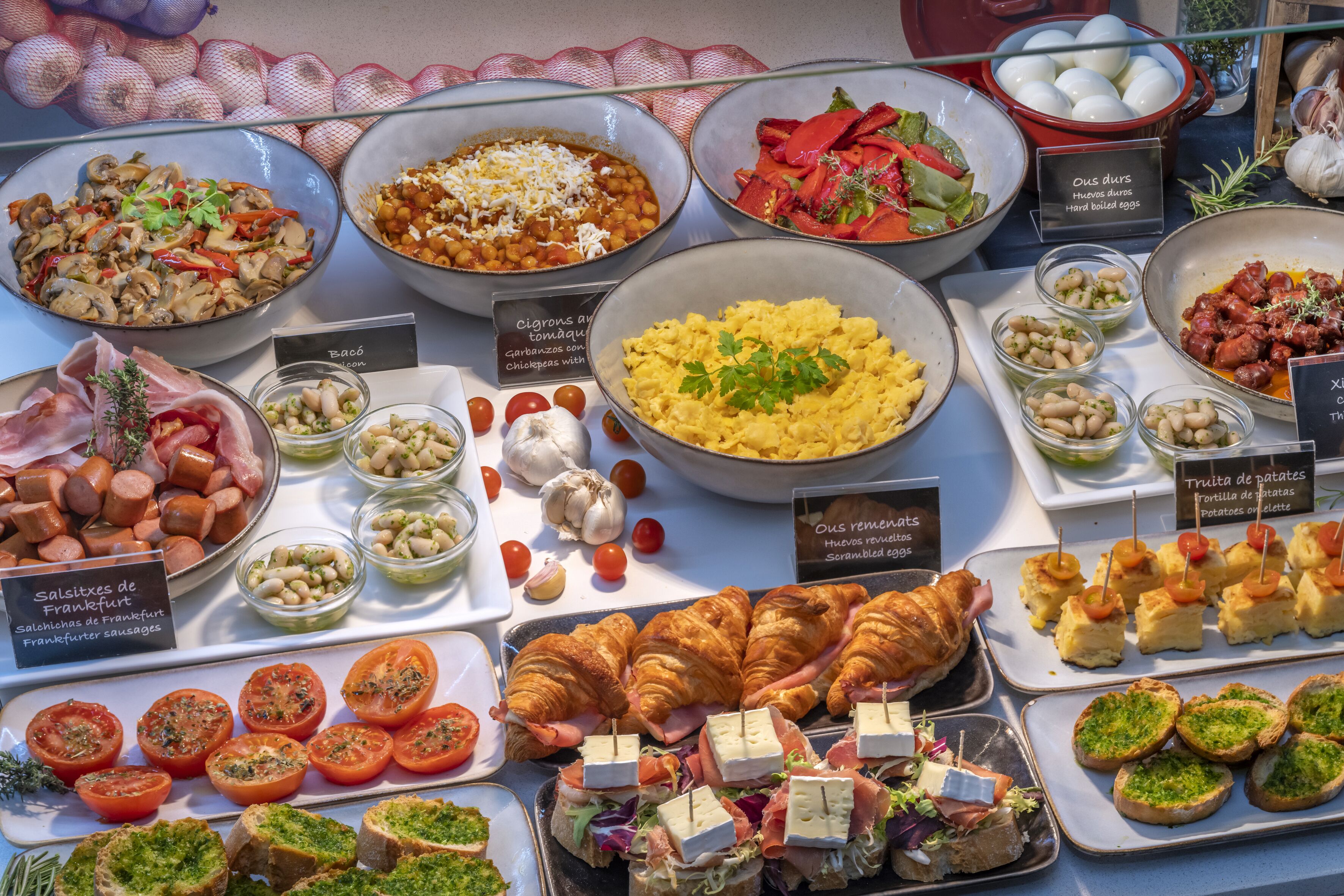 Un bufé con diferentes platos, incluyendo salchichas, huevos y ensaladas.
