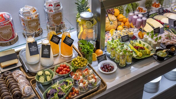 Un bufé con diversas opciones de comida, incluyendo frutas, quesos y pasteles.