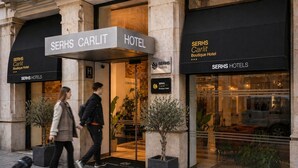 Entrada de un hotel con un letrero que dice 'SERHS Carlit Boutique Hotel' y un letrero de 'Coworking'.