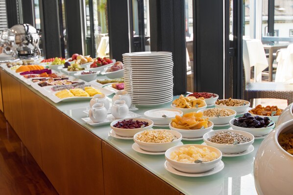A buffet with various food items and a stack of plates.