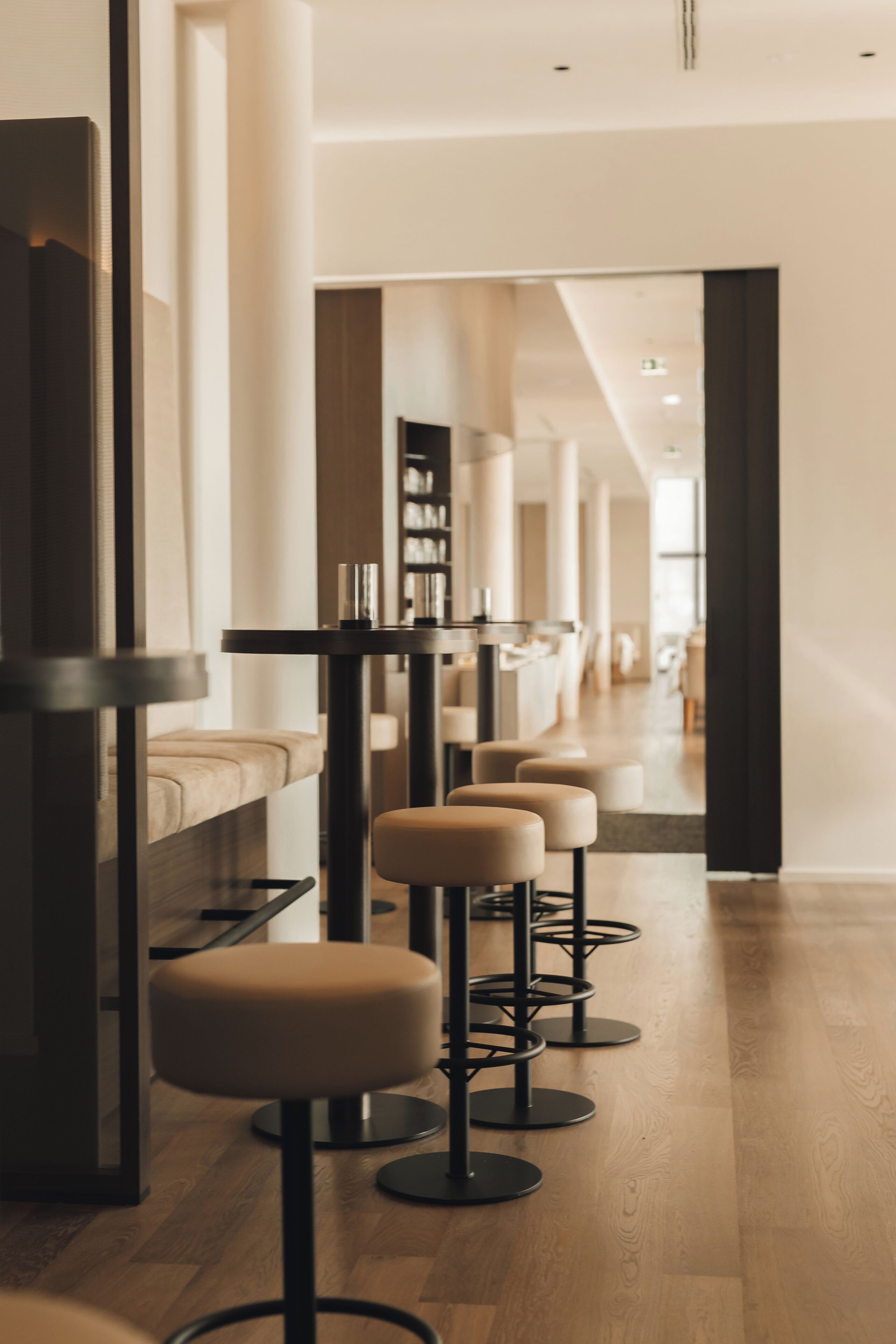 A modern interior with a row of bar stools, a sofa, and a bookshelf.