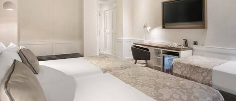 A hotel room with two beds, a desk, a television, and a coffee maker.