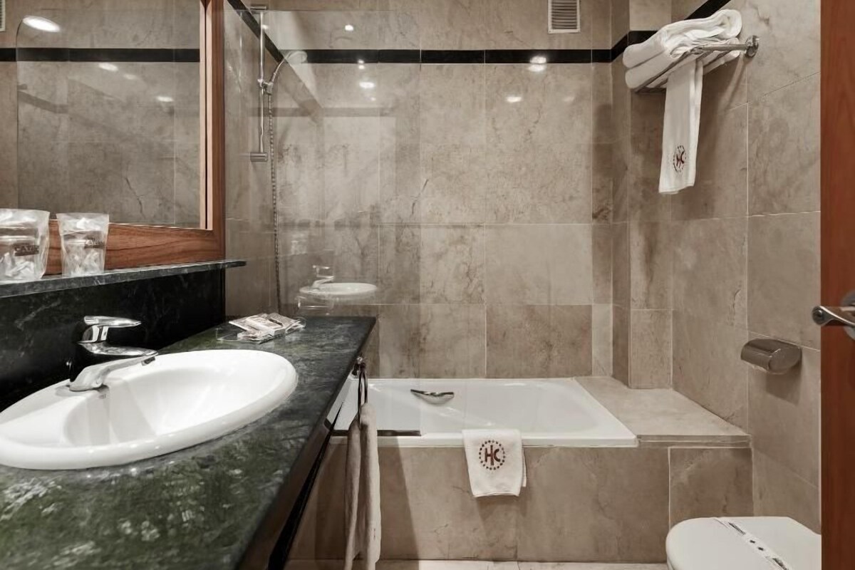 A bathroom with a sink, mirror, shower, and toilet.