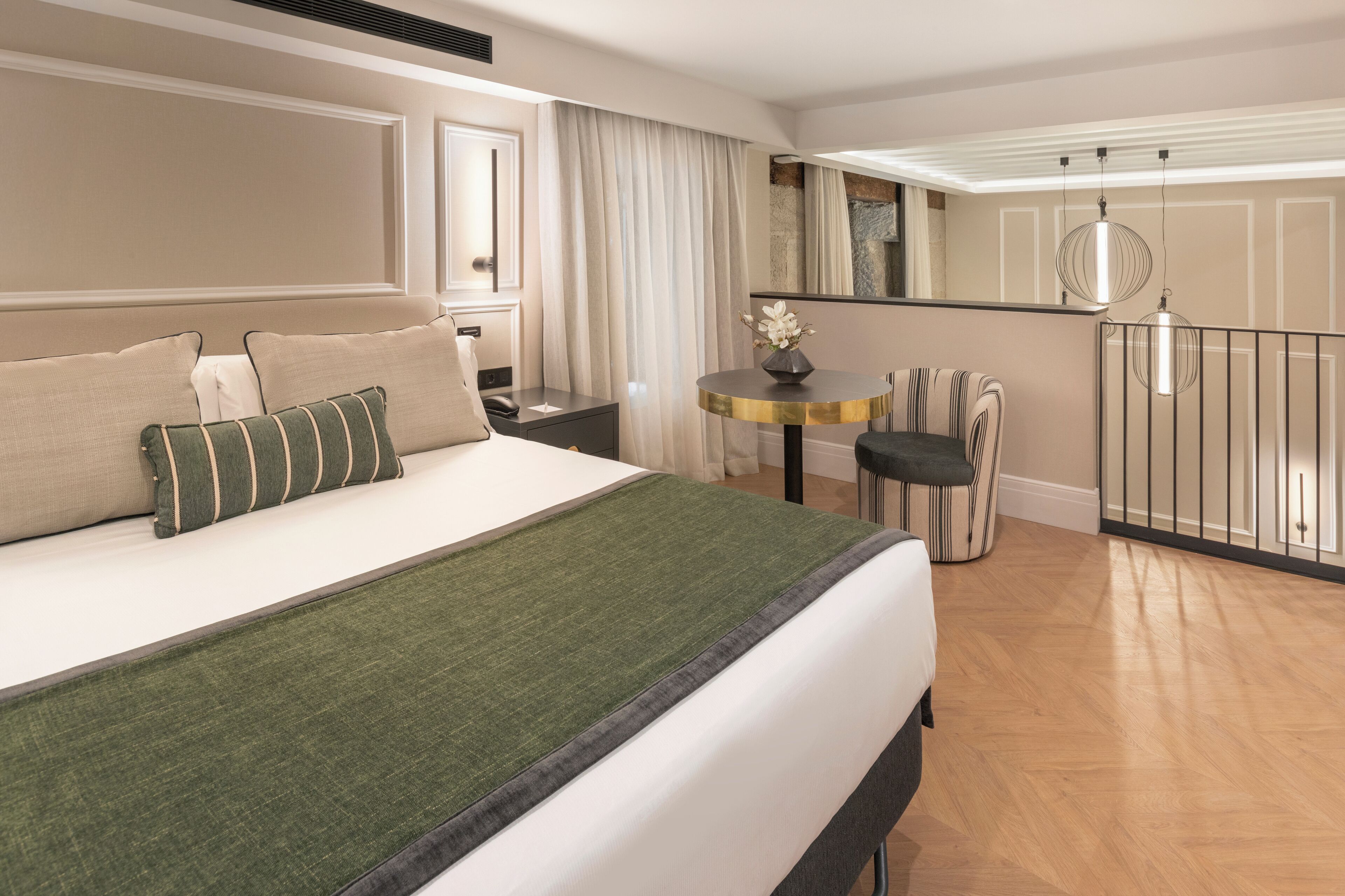 Hotellihuone, jossa on suuri sänky, pieni pöytä tuoleineen, parveke kaiteineen ja näkymä ulos.