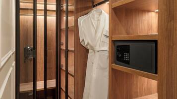 A hotel bathroom with a wooden vanity, a robe hanging on the wall, and a black microwave.